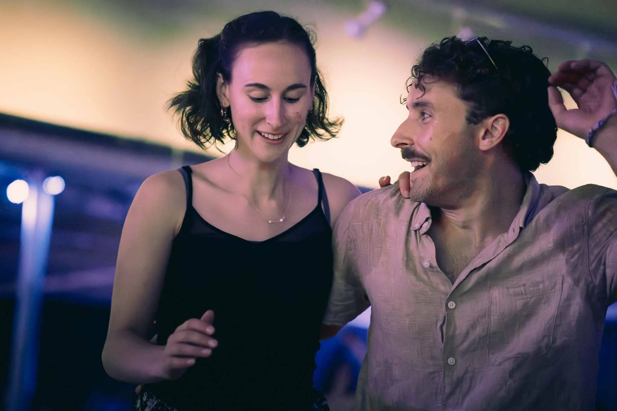 Swing dancers side-by-side with lead looking over at follow with a smile.